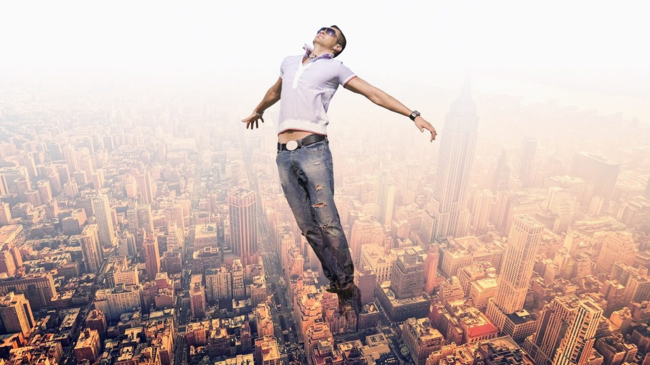 A person floating high above a city skyline with arms outstretched