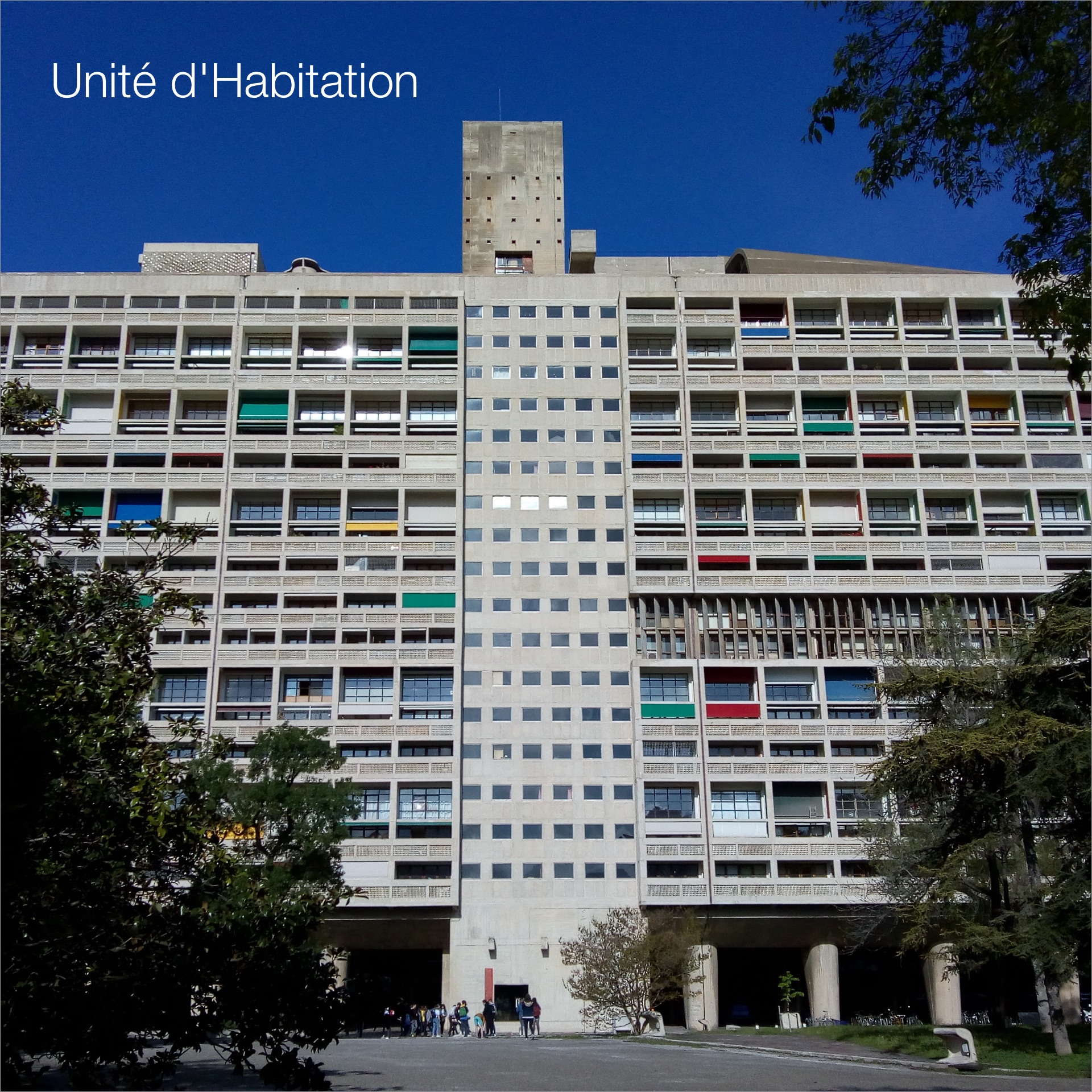 Le Corbusier's Unité d'Habitation, a concrete apartment block with coloured balconies, under a blue sky